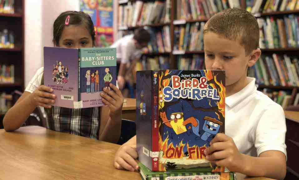 Two students reading books in library